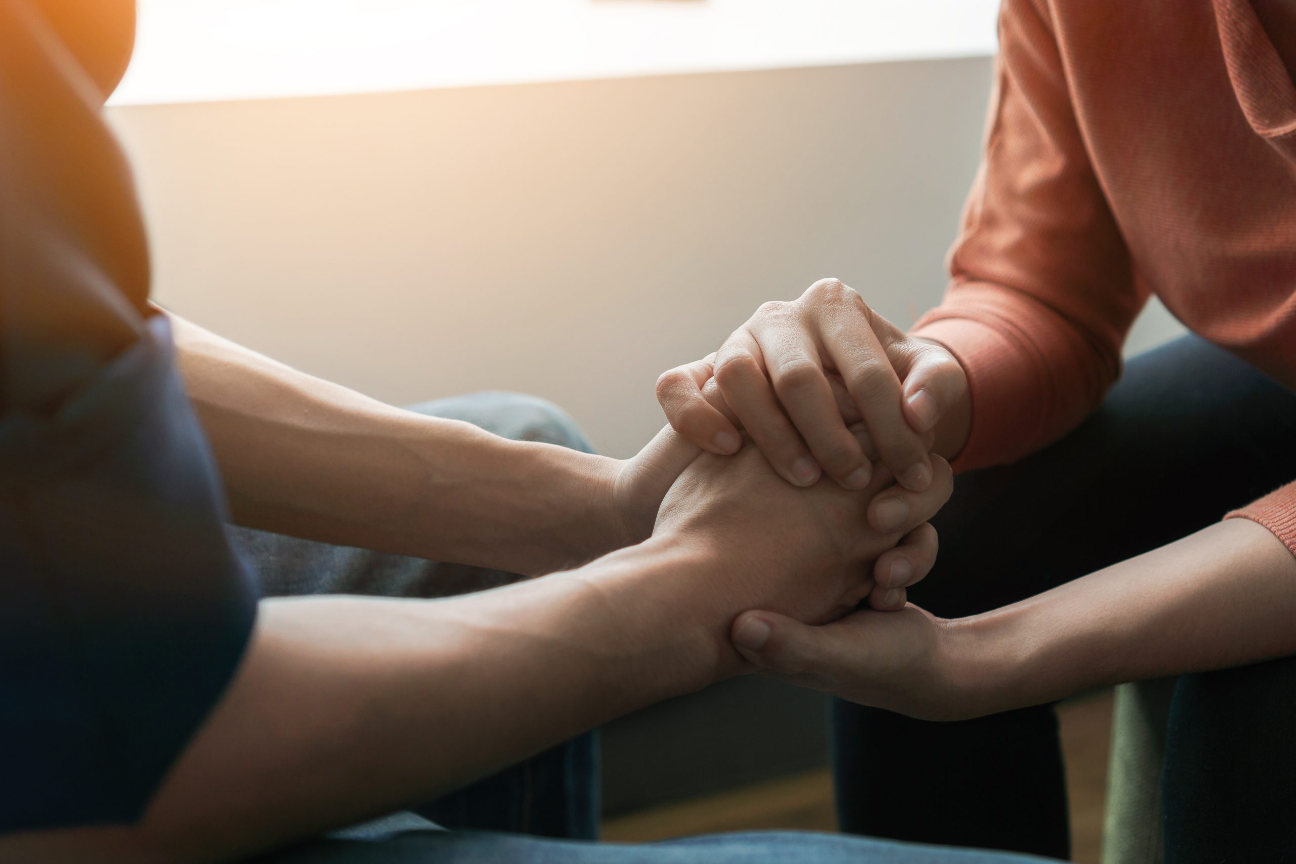 Psychologist sitting and touch hand young depressed asian man for encouragement near window with low light environment